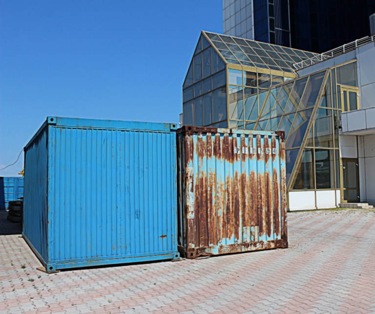 blue rusty shipping container outside a glasshouse