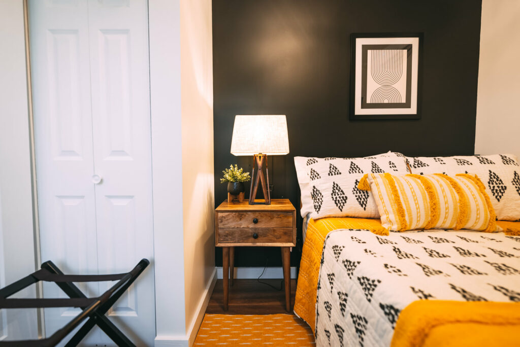 Regular-sized bed and wooden bedside table against black wall