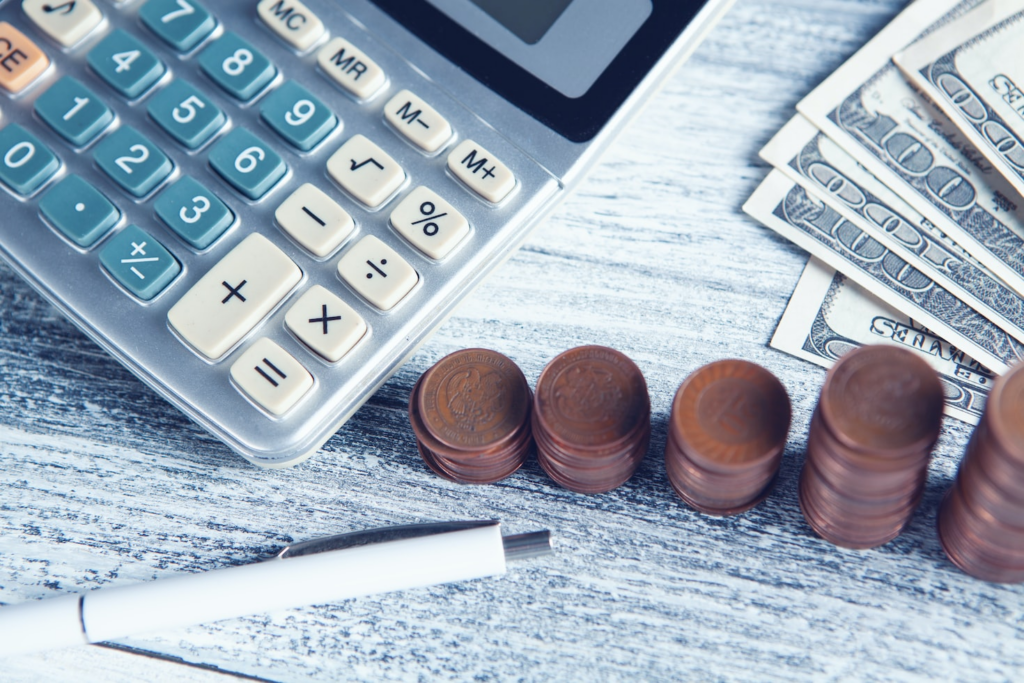 calculator with some dollar and coins on a table