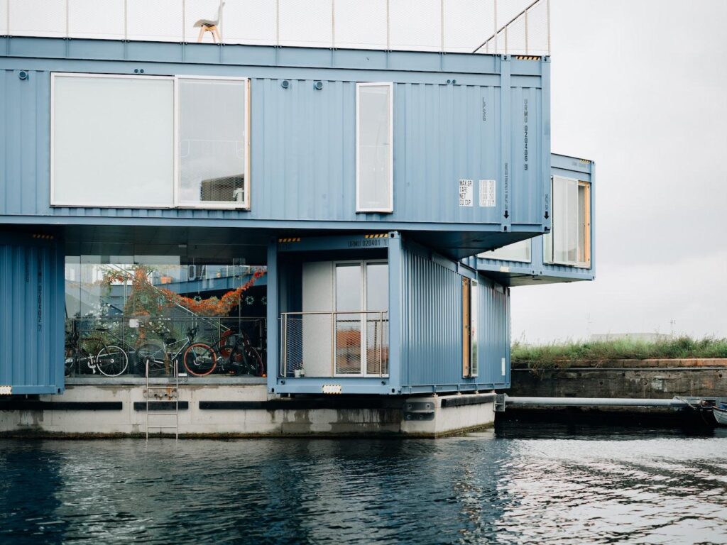 sky colored two storied container home beside a lake