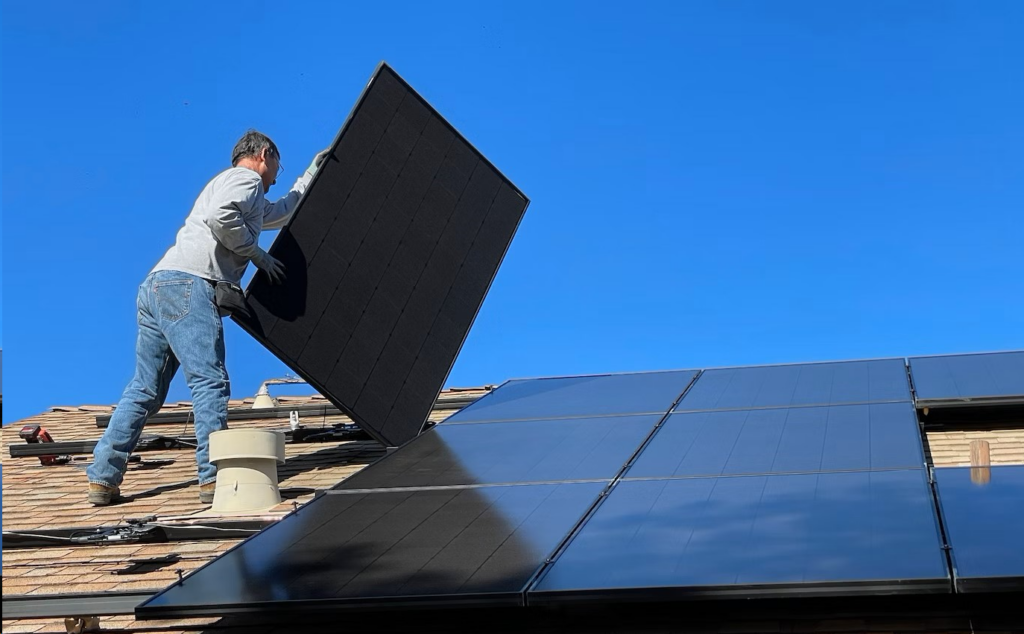 person placing solar panel on roof
