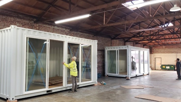 worker placing glass door in container home